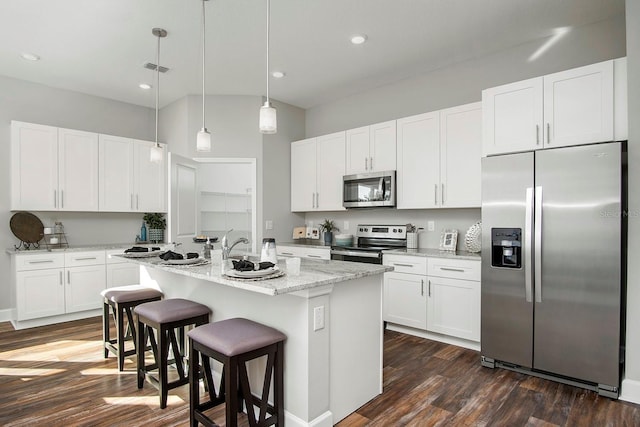 kitchen featuring dark wood finished floors, a center island with sink, a breakfast bar, hanging light fixtures, and stainless steel appliances