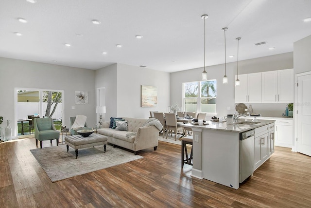 kitchen with dark wood-style floors, white cabinets, a kitchen island with sink, and stainless steel dishwasher