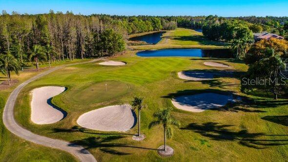 birds eye view of property with a water view, view of golf course, and a view of trees