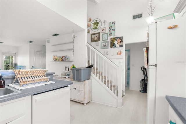 interior space with light wood-style flooring, white appliances, white cabinets, and visible vents