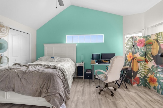 bedroom with a ceiling fan, lofted ceiling, a closet, and wood finished floors