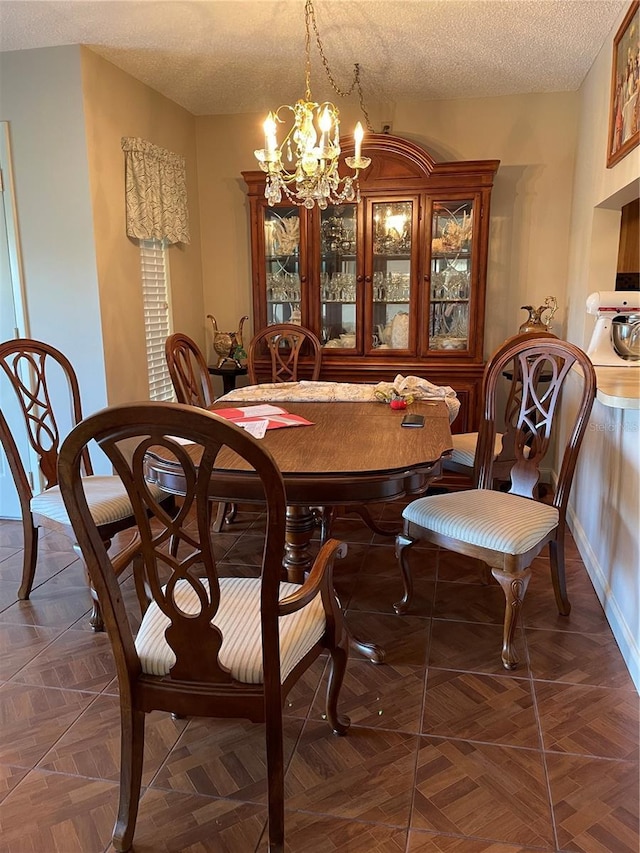 dining area featuring a chandelier, a textured ceiling, and baseboards