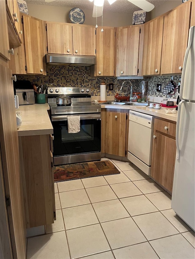 kitchen featuring under cabinet range hood, white appliances, light countertops, and light tile patterned floors