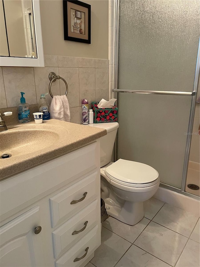 full bath with a shower stall, tile walls, toilet, tile patterned floors, and vanity