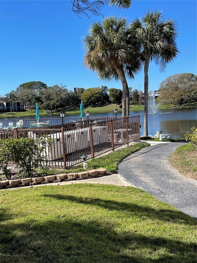 surrounding community featuring a yard, fence, and a water view