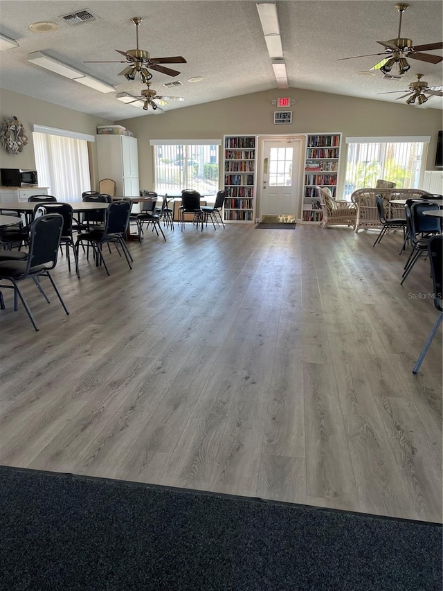 dining area featuring vaulted ceiling, wood finished floors, visible vents, and a wealth of natural light