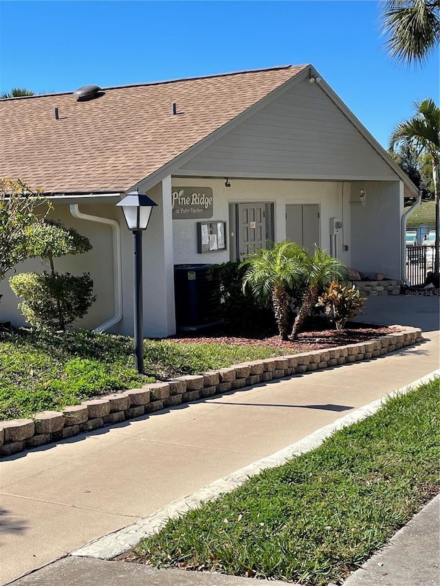 view of front of house featuring stucco siding and roof with shingles