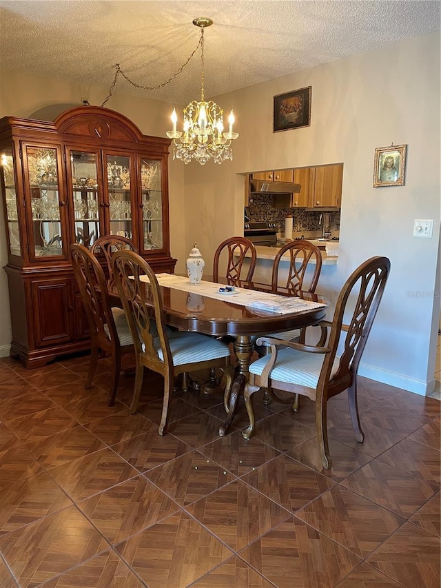 dining room with baseboards, a textured ceiling, and a notable chandelier