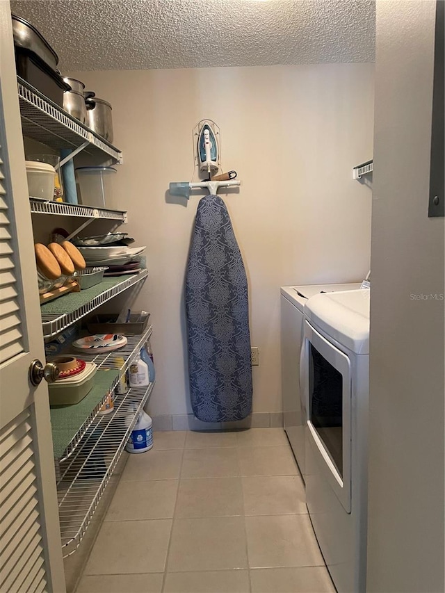 washroom featuring tile patterned floors, washer and clothes dryer, laundry area, and a textured ceiling