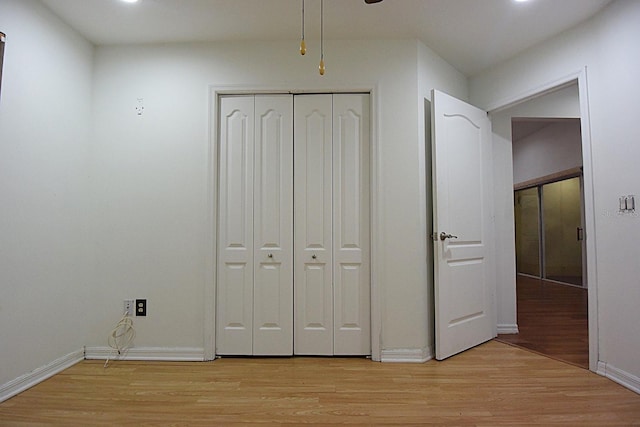 unfurnished bedroom with light wood-style floors, baseboards, and a closet