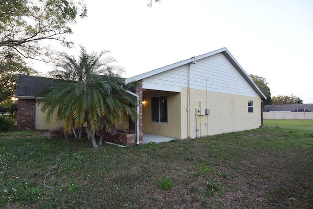 rear view of house featuring stucco siding, a patio, and a lawn