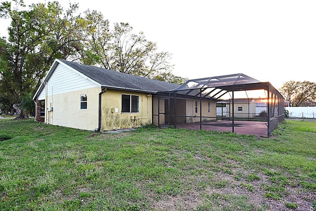 rear view of house with glass enclosure, fence, a lawn, and a patio