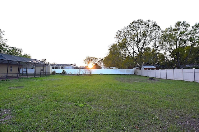 view of yard with glass enclosure and a fenced backyard