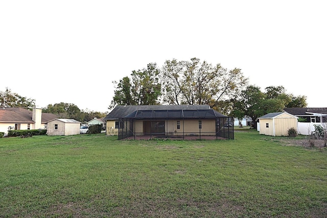 rear view of property with a yard, glass enclosure, an outdoor structure, and a storage unit