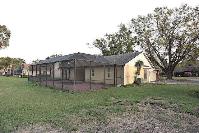 exterior space with glass enclosure, central AC unit, and a lawn