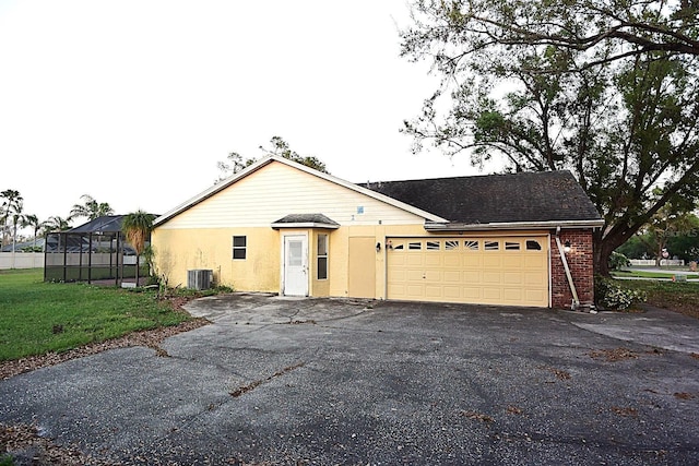 view of front facade with aphalt driveway, brick siding, a front yard, central AC, and a garage