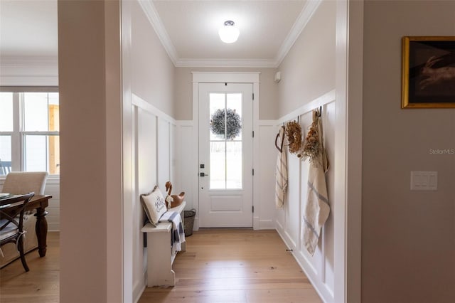 doorway featuring light wood-style flooring, a decorative wall, a wainscoted wall, and ornamental molding