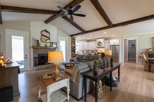 living area with ceiling fan, lofted ceiling with beams, recessed lighting, light wood-style flooring, and a fireplace