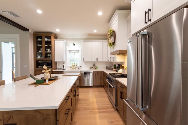 kitchen featuring visible vents, high quality appliances, light wood-type flooring, light countertops, and white cabinetry