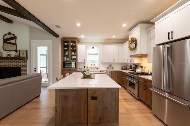 kitchen with light wood finished floors, open floor plan, white cabinets, and high end appliances