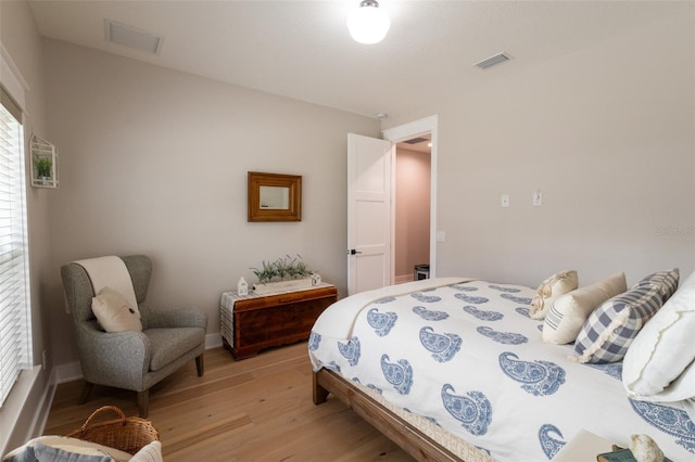 bedroom with visible vents, light wood-type flooring, and baseboards