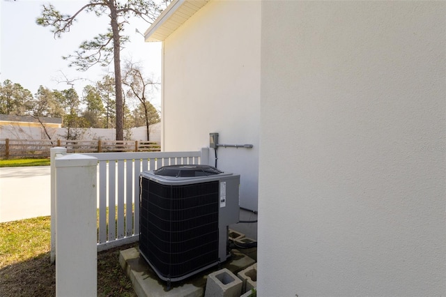 details with central AC unit, fence, and stucco siding