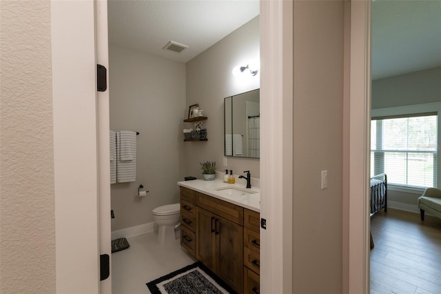 bathroom featuring visible vents, toilet, vanity, and baseboards