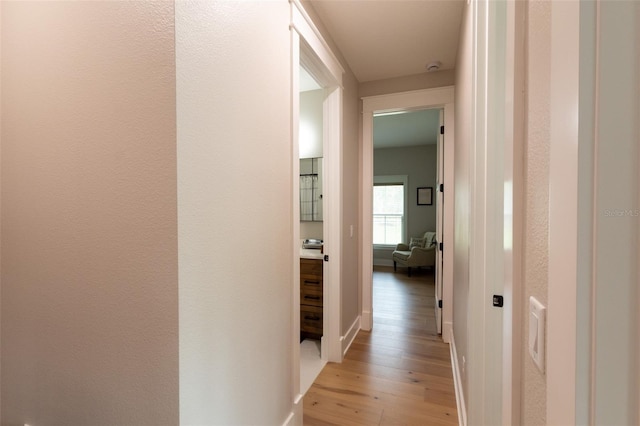 hall featuring baseboards and light wood finished floors