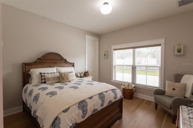 bedroom with visible vents, light wood-type flooring, and baseboards