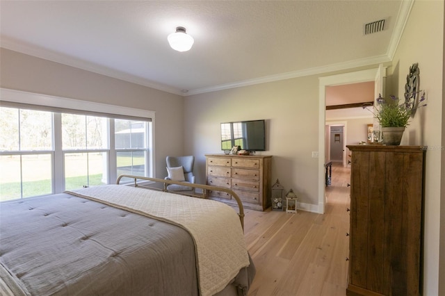 bedroom with crown molding, baseboards, visible vents, and light wood-type flooring