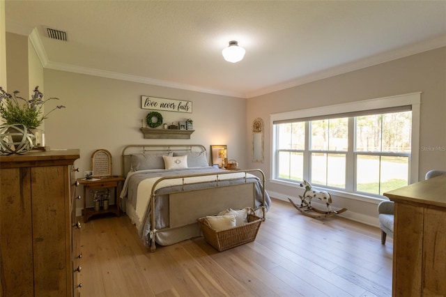 bedroom with visible vents, baseboards, wood finished floors, and crown molding