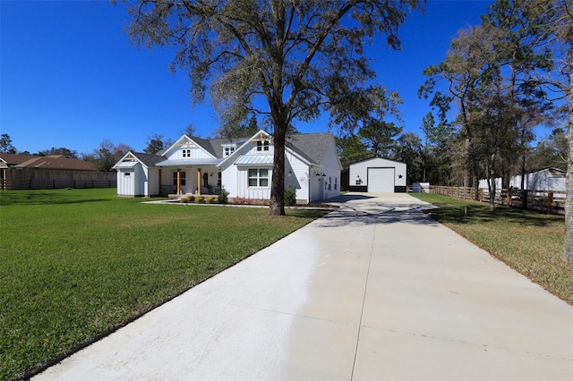 view of front of property with a front yard, fence, an outdoor structure, concrete driveway, and a detached garage