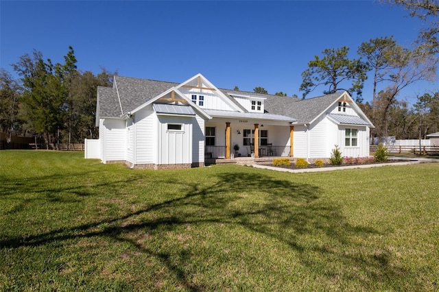 modern farmhouse featuring a front lawn, a porch, fence, board and batten siding, and metal roof