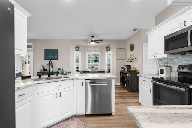 kitchen with visible vents, light wood-style flooring, a sink, tasteful backsplash, and stainless steel appliances