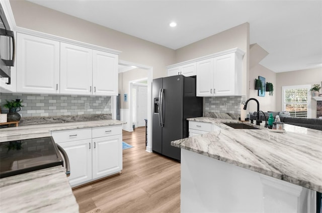 kitchen with fridge with ice dispenser, light wood-style floors, white cabinets, and a sink