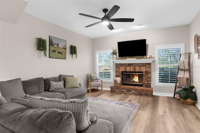 living area featuring a fireplace, baseboards, ceiling fan, and wood finished floors