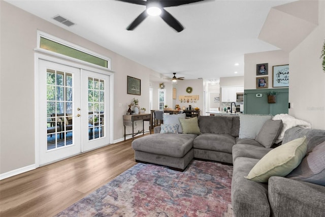 living room featuring visible vents, french doors, baseboards, and wood finished floors