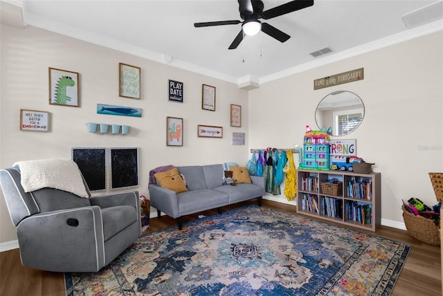 living area with visible vents, wood finished floors, baseboards, and ornamental molding