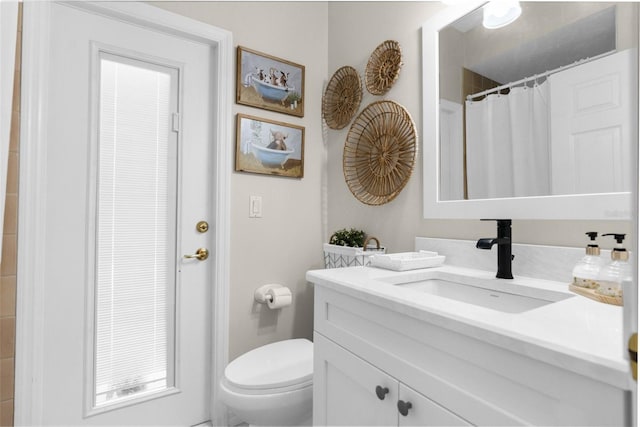 bathroom with curtained shower, toilet, and vanity