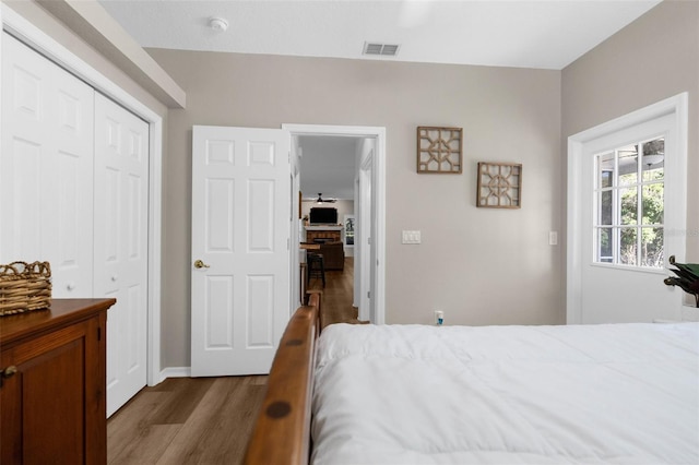 bedroom with dark wood-style floors, visible vents, and a closet