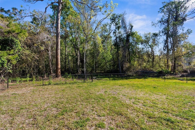 view of yard featuring a forest view and fence