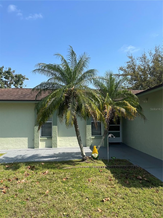 view of side of property with stucco siding and a lawn