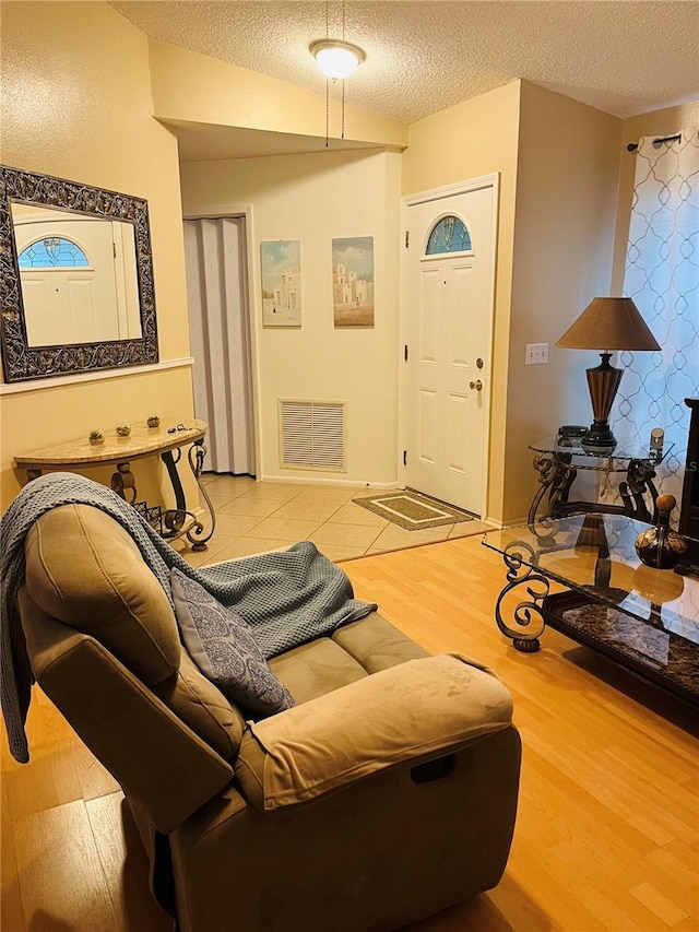 living room with baseboards, wood finished floors, visible vents, and a textured ceiling