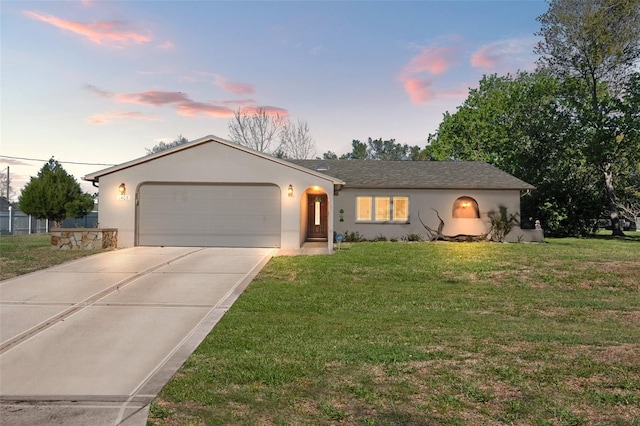 ranch-style house with stucco siding, driveway, an attached garage, and a front yard