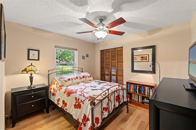 bedroom featuring a closet, a textured ceiling, a ceiling fan, and light wood finished floors