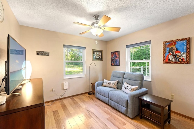 living room with baseboards, a healthy amount of sunlight, light wood-style flooring, and a ceiling fan