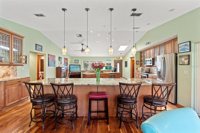 kitchen featuring a large island, visible vents, vaulted ceiling with skylight, and appliances with stainless steel finishes