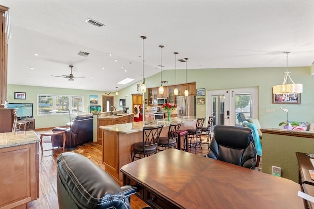 dining area with light wood finished floors, visible vents, french doors, and lofted ceiling