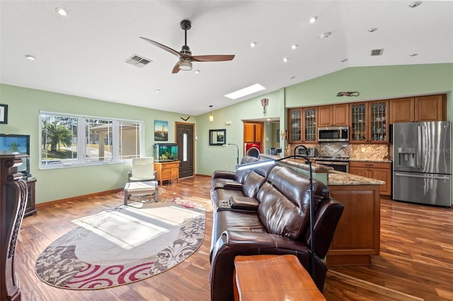 living area with lofted ceiling with skylight, wood finished floors, and visible vents