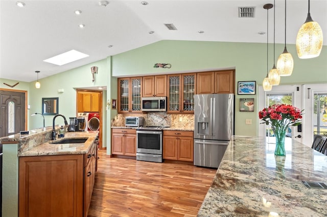 kitchen with a sink, stainless steel appliances, visible vents, and brown cabinetry